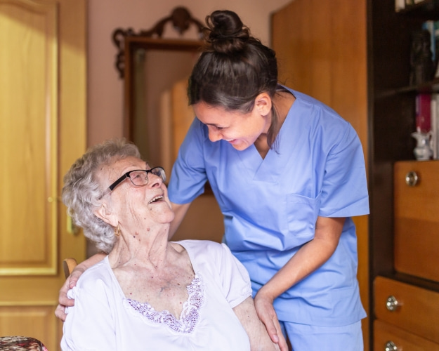 Nurse consoling senior woman holding her hand