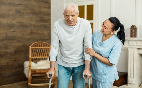 Professional helpful caregiver and a senior man during home visit