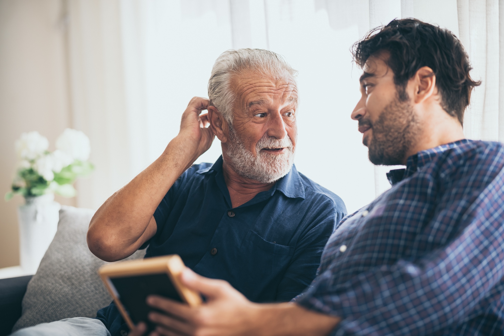An adult son and senior father at home, talking.